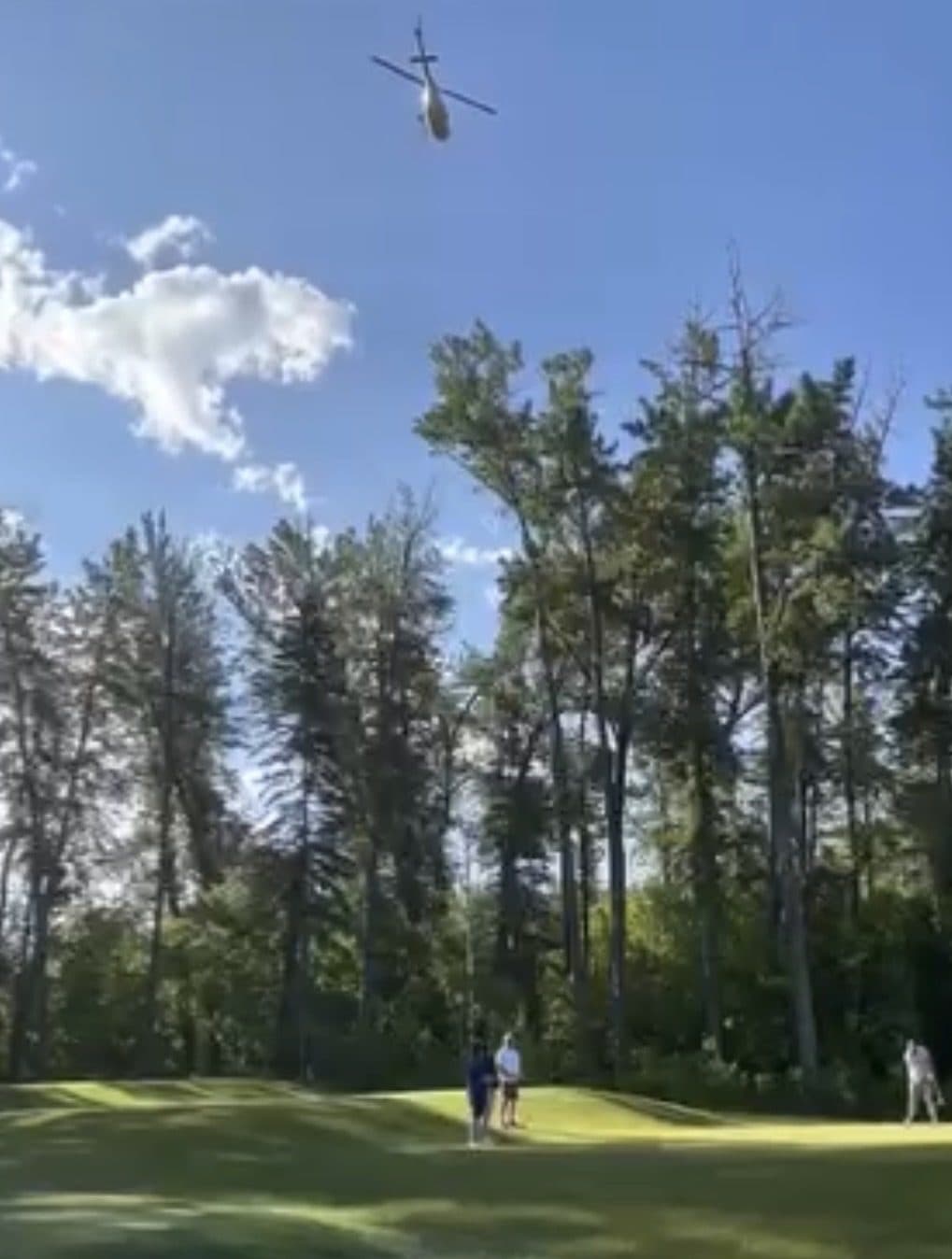 A helicopter above the trees at a golf course during the charity tournament.