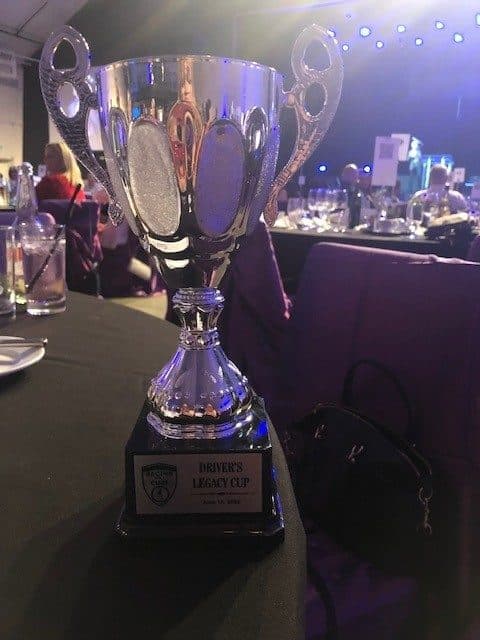 The Driver’s Legacy Cup trophy on a table at a Racing for a Cure gala.